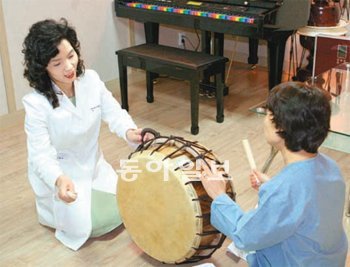 환자가 북을 두드리도록 하면서 음악치료를 진행하는 이승현 교수(왼쪽). 세종문화회관 제공