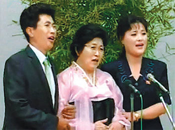 박인숙 씨(가운데)가 지난달 28일 평양에서 기자회견을 하는 도중에 아들 며느리와 함께 김정은의 은혜를 칭송하는 노래를 부르고 있다. 조선중앙TV 화면 촬영