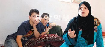 지난해 11월 시리아 반군이던 아버지가 숨진 뒤 요르단으로 탈출한 소년 아사드(왼쪽)와 그의 동생, 어머니. 이들은 아사드가 슈퍼마켓에서 물건을 나르며 벌어온 일당 4800원으로 겨우 살아간다. 마프라끄=이종훈 특파원 taylor55@donga.com