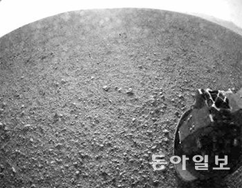 6일 오후 2시 32분(한국 시간) 화성의 게일 분화구에 도착한 ‘큐리오시티’가 착륙한 직후 찍어 보내온 흑백 사진. 화성 표면에 있는 작은 돌과 흙 알갱이까지 세세하게 보인다. 오른쪽 아래 보이는 물체는 큐리오시티의 바퀴다. NASA 제공