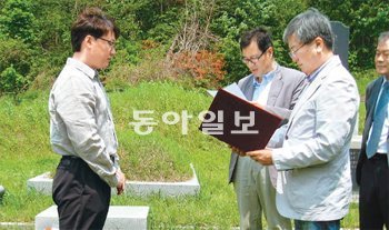 세상을 떠난 스승을 추모하기 위해 24년째 장학금을 운영해온 제자들이 있다. 장학회 대표를 맡았던 전웅수 단국대 교수(오른쪽)가 지난해 5월 스승 고정섭 서강대 교수의 산소 앞에서 장학증서를 주고 있다. 전웅수 교수 제공