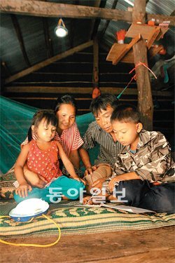 캄보디아 반티민체이 주 꼰뜨레이 지역 농촌 마을에 사는 한 가족이 새로 설치한 태양광램프 아래서 책을 읽고 있다. 굿네이버스 제공