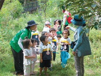 숲해설가가 어린이들에게 야생 꽃을 소개하는 모습.