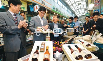 하성민 SK텔레콤 사장(왼쪽에서 두 번째)이 26일 전통시장 활성화 지원 협약식을 가진 뒤 온라인 쇼핑몰 11번가에서 판매할 중곡제일시장 자체 제작 참기름을 살펴보고 있다. 김미옥 기자 salt@donga.com