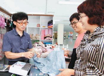 이달 준공한 서문시장 2지구 1층 상가에서 처음 장사를 시작한 정규태 씨(왼쪽)가 고객에게 속옷 상품을 설명하고 있다. 장영훈 기자 jang@donga.com