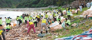 부산외국어대생 70여 명이 일본 쓰시마 섬 동북쪽 이구치하마 해변에서 쓰시마 현지 고교생과 자원봉사자와 함께 해변으로 밀려든 쓰레기를 수거하고 있다. 부산외국어대 제공
