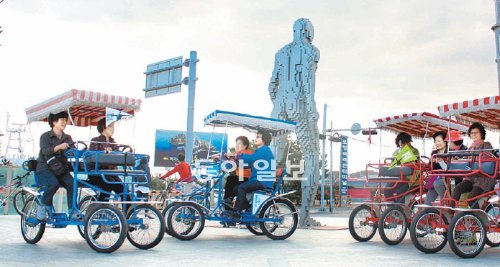 20일 경북 포항시 북구 항구동 스틸아트페스티벌 전시장에서 자전거를 타는 관람객들이 인간 모양의 대형 작품 옆을 지나고 있다. 포항시 제공