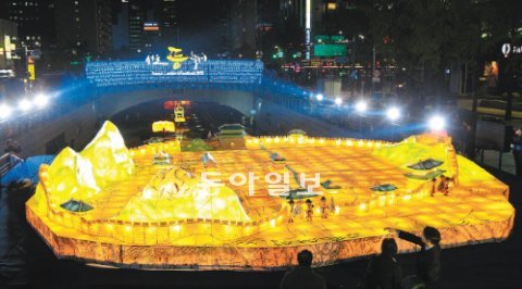 청계광장에 ‘한양도성등’ ‘2012 서울등축제’ 개막을 하루 앞둔 1일 오후 시민들이 청계광장 분수대 위에 띄워진 ‘한양도성등’을 바라보고 있다. 경복궁과 보신각 등 한양도성 내 주요 건물을 표현한 등이 눈에 띈다. 이번 축제는 2∼18일 청계천 일대에서 펼쳐진다. 김재명 기자 base@donga.com