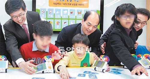 하성민 SK텔레콤 사장(뒷줄 왼쪽), 강병두 서울정진학교장(뒷줄 왼쪽에서 두 번째) 등이 스마트 로봇을 이용해 한글을 익히는 장애학생들을 지켜보고 있다. SK텔레콤 제공