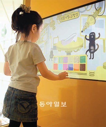 ‘더 놀자’를 찾은 아이가 신발을 디자인하기 위해 터치스크린에서 색상을 고르고 있다. 넥슨 제공
