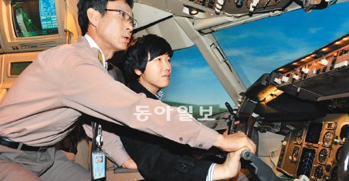 지난달 21일 서울 강서구 오쇠동 아시아나항공 본사의 B767-300 시뮬레이터 안에서 이 회사 운항훈련팀 이근우 기장(왼쪽)이 조종석에 앉은 기자에게 항공기 조종법을 알려주고 있다. 아시아나항공 제공