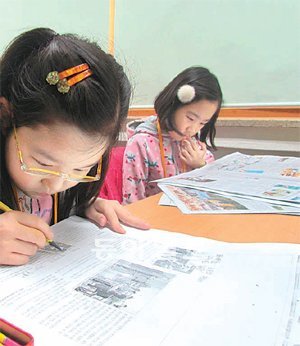 수업에서 자신이 쓴 기사가 실린 신문을 살펴보는 학생들.