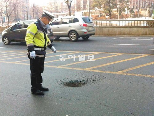 15일 교통경찰관이 인천 남구 주안동 옛 시민회관 앞 도로에서 움푹 파인 곳을 가리키고있다. 인천시의 도로 보수 예산이 충분치 않아 폭설과 한파로 인해 파손된 도로가 방치돼 운전자들이 불편을 겪고 있다. 인천경찰청 제공