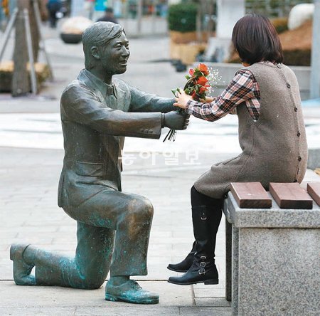 꽃다발은 셀프 한 여성이 지난달 22일 서울 중구 예관동 중구청 광장 앞 ‘프러포즈’ 동상에서 꽃을 받는 모습을 연출하고 있다. 장승윤 기자 tomato99@donga.com