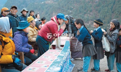 네팔 히말라야 쿰부히말에 있는 스리페마촐링 초등학교 학생들이 한국에서 온 오지마을 체험단을 환영하는 뜻을 담은 카타를 걸어주고 있다. 가운데에 손을 모으고 감사를 표하는 이가 박연수 체험단장. 쿰부히말=장기우 기자 straw825@donga.com