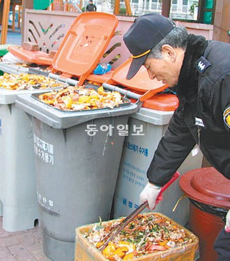 부산 금정구 한 아파트 경비원이 수거해 가지 않아 넘쳐나고 있는 음식물 쓰레기를 정리하고 있다. 조용휘 기자 silent@donga.com