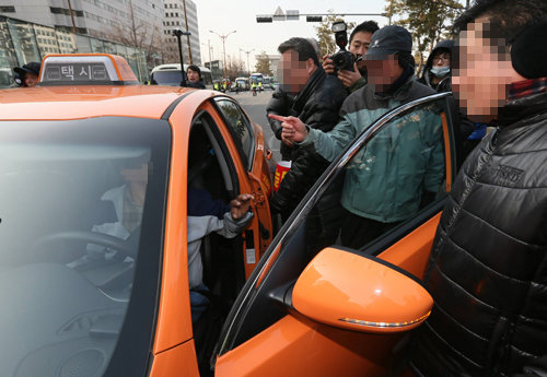 택시업계 비상합동총회에 참가한 택시업계 종사자들이 20일 오후 서울 여의도 국회 앞에서 해산하던 중 운행중인 택시를 막아서고 문을 연 뒤 기사에게 항의하고 있다. (서울=연합뉴스)