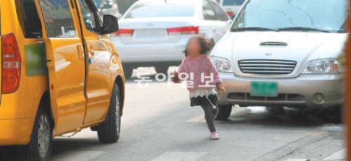 27일 오후 한 어린이가 서울 양천구 도로에서 인도에서 떨어져 정차한 학원차량에 타기 위해 차량 사이를 뛰어가고 있다. 인솔자는 보이지 않았다. 변영욱 기자 cut@donga.com