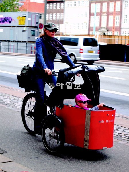 덴마크의 한 여성이 아이를 자전거 유모차에 태우고 도심을 달리고 있다. 북유럽의 엄마 아빠들은 영하의 날씨에도 아이를 유모차에서 재우는가 하면, 비가와도 비닐덮개를 씌우고 산책을 다닌다. 네시간 제공