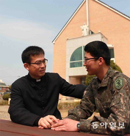 군종신부인 최병규 대위(왼쪽)가 23사단 성당 앞에서 병사들과 대화하고 있다. 최 대위는 산악행군과 천리행군을 병사들과 함께 하며 그들을 격려한다. 육군 23사단 제공