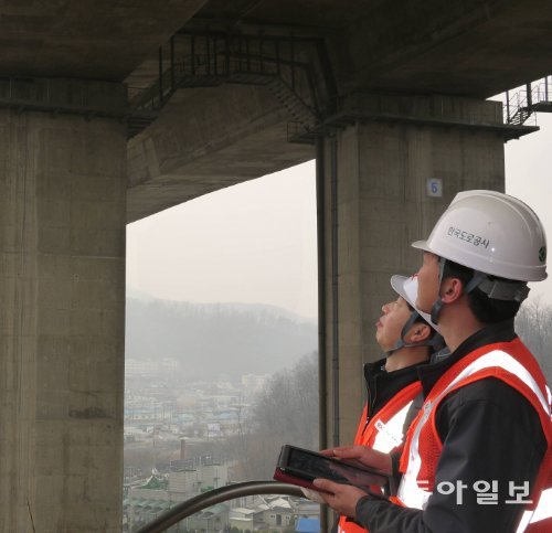 안양고가 밑에서 한국도로공사 직원들이 태블릿PC에 내장된 ‘시설물 점검 애플리케이션’으로 교량을 점검하고 있다. 안양=김철중 기자 tnf@donga.com