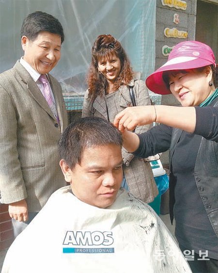 박경규 목사(왼쪽)가 교회 안마당에서 홍미용실 홍동화 원장(오른쪽)이 외국인노동자의 머리를 깎아주는 모습을 지켜보고 있다. 지명훈 기자 mhjee@donga.com