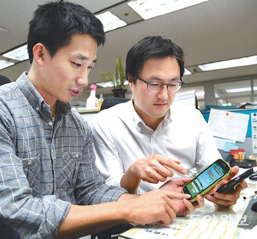 송충현 기자(왼쪽)가 최근 다이어트를 결심한 동료에게 스마트폰 적금 사용법을 알려주고 있다. 친구에게 같은 종류의 스마트폰 적금을 추천해 가입시키면 우대금리를 적용해주는 은행도 많다.