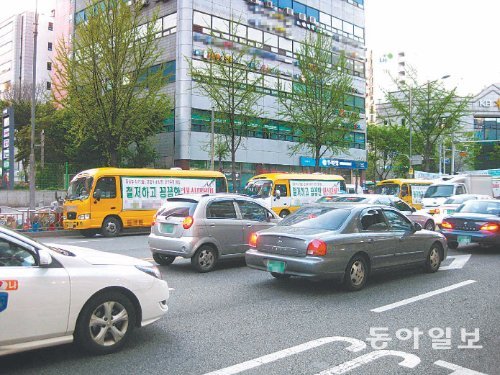 학원 380곳이 밀집한 서울 노원구 중계동 은행사거리 앞 대로변에 노란색 학원버스가 한 차로를 점령한 채 줄지
어 늘어서 있다. 이로 인한 시민 불편을 막기 위해 학원버스를 노선별로 통합 운영해 버스 대수를 줄이자는 논의
가 진행 중이다. 박진우 기자 pjw@donga.com