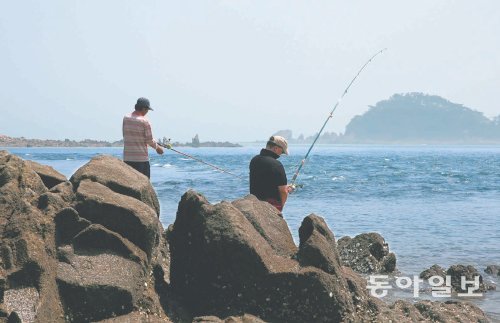 소야도 갯바위 낚시 포인트에서 낚시꾼 2명이 릴낚시를 하고 있다. 이 해안가는 하루 2차례 바다 갈림길 현상이 일어나 앞에 보이는 가섬, 간데섬, 물푸레섬을 걸어서 건너갈 수 있다. 인천 옹진군 제공
