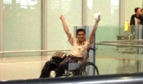중국 베이징 서우두 공항에서 20일 오후 치안대원의 폭행으로 하반신이 마비된 지중싱 씨가 두 손을 번쩍 들어 자신의 억울함을 호소하고 있다. 사진출처 웨이보