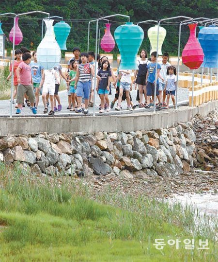 고려청자의 고장 전남 강진에서 청자축제가 27일 개막된다. 축제를 앞두고 24일 전남 강진군 대구면 청자촌 해안도로에 LED 전구를 이용한 대형 오색 청자조형물이 설치돼 이곳을 찾은 어린이들이 등을 살펴보고 있다. 박영철 기자 skyblue@donga.com