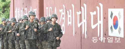 JSA 대원들이 ‘대한민국 대표 JSA 경비대대’라는 문구와 태극기가 그려진 영내 시설물을
 배경으로 완전군장 구보를 하고 있다. 판문점=신원건 기자 laputa@donga.com