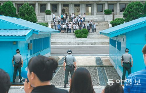 18일 오전 판문점 공동경비구역 내 자유의 집을 찾은 남측 방문객들과 건너편 판문각 앞에 나타난 북측 방문객들이 눈앞의 군사분계선을 사이에 두고 서로 쳐다보고 있다. 양측의 거리는 80m 안팎에 불과했지만 남과 북 사이를 가른 채 버티고 선 보이지 않는 거대한 장벽은 분단과 정전 60년의 아픔을 생생히 대변하고 있었다. 판문점=신원건 기자 laputa@donga.com