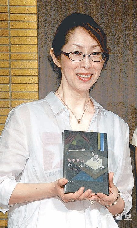 올해 일본 문학상 나오키상을 수상한 사쿠라기 시노 씨가 기자회견에서 수상작 ‘호텔 로열’을 들고있다. 아사히신문 제공