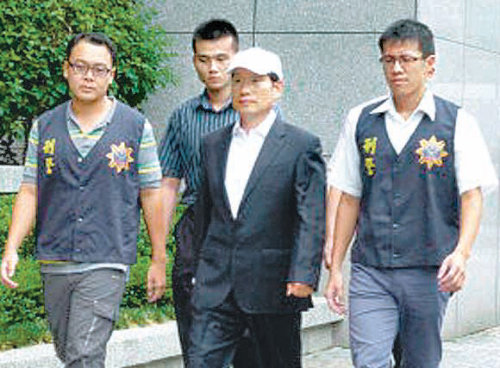 김원홍 전 SK해운 고문(가운데 모자 쓴 사람)이 지난달 31일 대만 현지 경찰에 체포된 뒤 경찰과 함께 걸어가는 모습. 대만 현지언론 보도화면 캡처