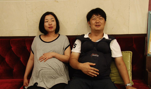임신 8개월인 아내(왼쪽)의 ‘임산부 고충’을 느껴보겠다며 도전에 나선 홍성진 PD가 10kg의 체험복을 입은 채 힘겨워 하고 있다. 사진제공｜채널A