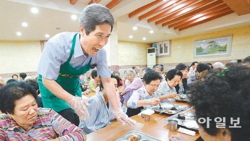 한길봉사회 김종은 회장(서 있는 사람)은 매일 점심 할머니 할아버지들에게 무료 급식을 하고 있다. 김 회장이 할머니에게 식사를 가져다 드리며 웃고 있다. 원대연 기자 yeon72@donga.com