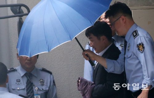 이석기 얼굴 가려라” 우산 펴든 교도관 14일 공판준비기일이 끝난 뒤 이석기 의원이 검은색 정장을 입고
 수갑 찬 두 손을 수건으로 가린 채 수원지법을 나서고 있다. 법원을 빠져나올 때 통합진보당 당원들이 “피의자의 인권을 
보호하라”고 소리치자 교도관이 이 의원의 얼굴을 가려주기 위해 우산을 씌운 채 이동했다. 수원=홍진환 기자 jean@donga.com