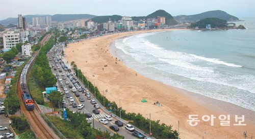 이웃한 해운대와 달리 철길로 기차가 달리는 한적하고 소박한 모래 해변 송정. 11월 30일 0시를 기해 이 철길이 폐쇄되면 이후엔 기차와 철길, 해변과 바다가 한데 어우러져 빚어 내는 이 풍경은 영원히 볼 수없게 된다. 전망카페 치엘로(7층)가 있는 빌딩 옥상에서 촬영. 부산=조성하 여행전문기자 summer@donga.com