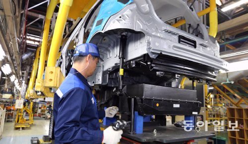 한국GM 창원공장의 한 근로자가 28일 스파크EV 차체에 전기자동차용 배터리(검은 상자 모양의 물건)를 끼우는 작업을 하고 있다. 한국GM 제공