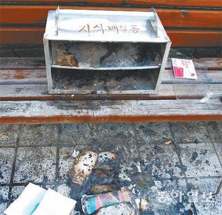 28일 오후 광주 서구 치평동 벤치에 놓여진 ‘지식배달통’과 안에 담겨 있던 책이 불에 탄 채 널브러져 있다. 신광조 씨 제공