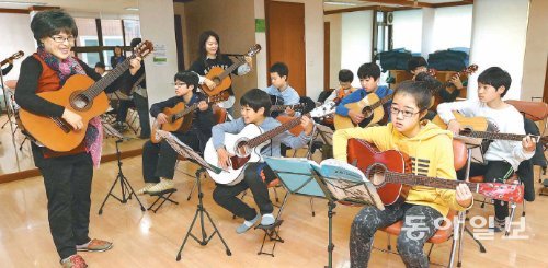 서울 노원구 포크기타음악 마을학교에서 어린이들이 구현순 씨(왼쪽)의 지도에 따라 기타를 연주하고 있다. 노원구에는 주민들이 지역 아이들을 위한 교사로
참여하는 마을학교 80곳이 운영되고 있다. 김재명 기자 base@donga.com