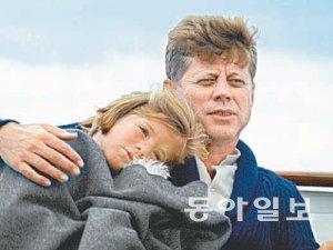 담요를 덮은 어린 캐럴라인이 아버지 존 F 케네디 대통령의 어깨에 기대어 쉬고 있다.