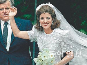 1986년 막내 삼촌 에드워드 케네디의 손을 잡고 입장한 결혼식장에서 하객들에게 손을 흔들고 있다.