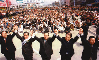 1996년 3월 29일 자유민주연합의 충북 제천시 정당연설회에서 김종필 당시 총재가 안영기 후보와 손을 마주 들고 청중의 환호에 답하고 있다.