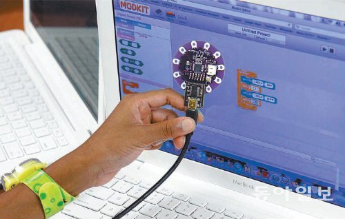 미국의 한 학생이 컴퓨터 화면으로 손에 든 전자 보드를 동작시키는 프로그래밍을 배우고 있다. 이러한 과정은 전자기기를 활용해 실생활의 복잡한 문제들을 해결하고 창의적인 사고력을 기르는 데 도움을 준다. 한국과학창의재단 제공