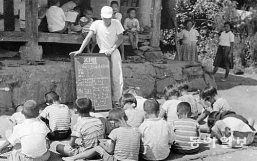 1954년 한 농촌에서 어린이들이 유네스코 학생건설대 대원의 지도 아래 땡볕이 내리쬐는 마당에 앉아 자못 진지하게 시험을 보고 있다. 유네스코 한국위원회 제공