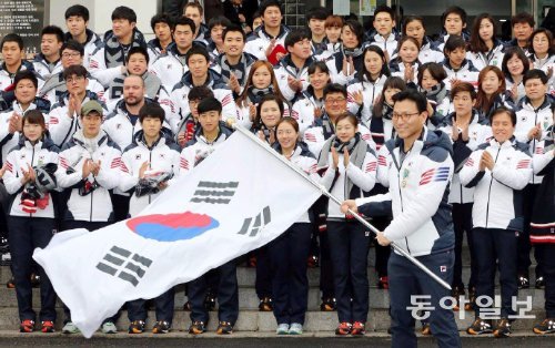 소치 겨울올림픽 국가대표 결단식에서 선수들이 박수를 보내는 가운데 김재열 선수단장이 태극기를 휘날리고 있다. 730명이 참가했던 생모리츠 대회에 3명(0.4%)을 파견했던 한국은 올해 71명(전체의 2.5%)의 태극전사가 출전했다.