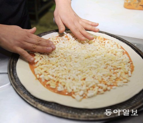 ‘착한 피자’에 100% 자연산 치즈를 토핑하는 모습.