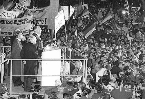 1989년 12월 19일 당시 동독 지역인 드레스덴을 찾은 헬무트 콜 서독 총리(연단 앞에 선 사람)가 프라우엔키르헤 교회의 폐허 돌무더기 앞에서 연설하고 있다. 연설을 듣고 있는 동독 주민들의 열렬한 반응이 인상적이다. 동아일보DB